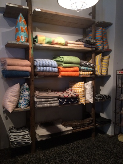 Ladder, shelving unit with display of colourful blankets and cushions