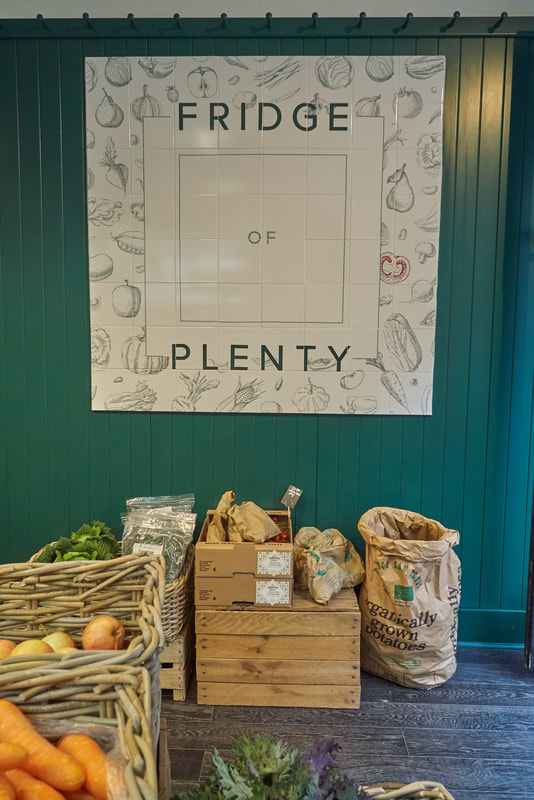 Bespoke tiled panel sign on green tongue and groove with shaker peg rail. Shop interior design by theopenplan.com