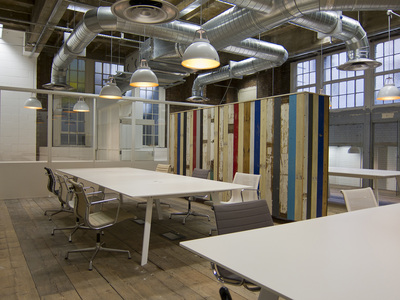 Cool offices with minimal white desks by Modus, Eames swivel chairs and bespoke cupboards and room dividers made from reclaimed wood