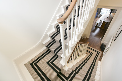 Off-white hallway with Hartley and Tissier cream and black, striped stair runner in Islington, London, UK