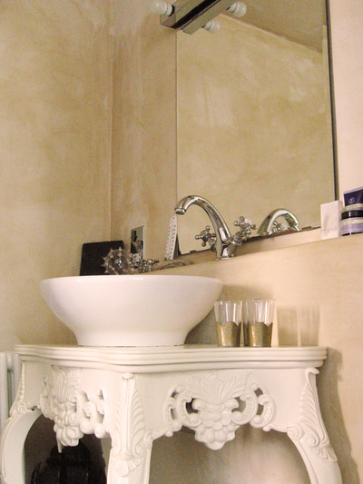 Tadelakt walls in a French Moroccan bathroom with a table top sink on an ornate, white painted console table