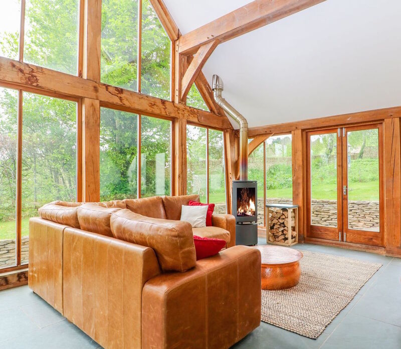 Oak framed conservatory with brown leather, L shaped sofa, copper coffee table, recycled leather rug and wood fuelled stove
