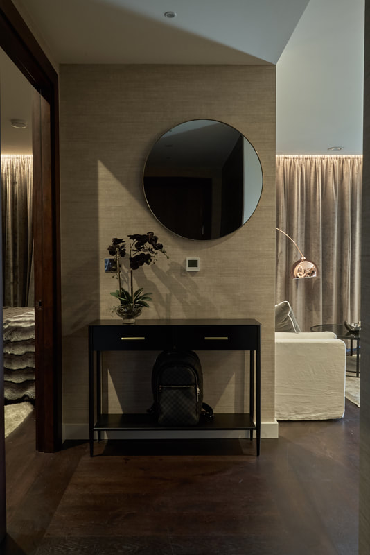 Black metal console table with brass handles and large round mirror in compact hallway in Battersea, London, UK