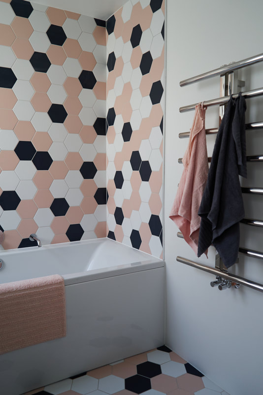 Family bathroom in Stoke Newington, with pink, white and navy hexagonal wall and floor tiles and a Chrome, minimal towel rail from Lusso Stone 