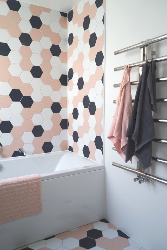 Children's Bathroom with pink, blue and white hexagonal tiles and chrome, wall mounted towel rail with pink and blue towels