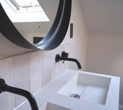 Modern white bathroom with white zellige tiles, double sink, black taps and round black mirror