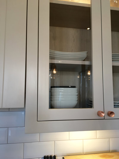 Glazed wall cupboards with copper handles and white brick bonded, Metro tiles